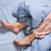 Weibliche Füße mit Schlafanzug im Bett am Morgen