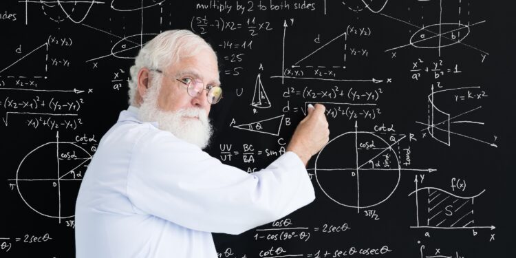Eine älterer Mann schreibt mathematische Gleichungen an eine Tafel.