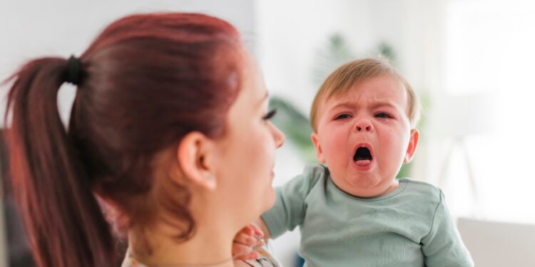 Eine Mutter hält ein hustendes Baby im Arm.