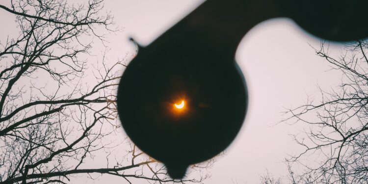 Eine partielle Sonnenfinsternis durch eine Schutzbrille betrachtet