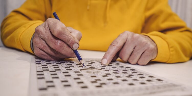 Ein Senior löst ein Kreuzworträtsel.
