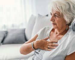 Eine ältere Frau mit Sodbrennen fasst sich an die Brust