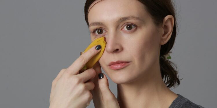 Frau reibt ein Stück Bananenschale über ihr Gesicht