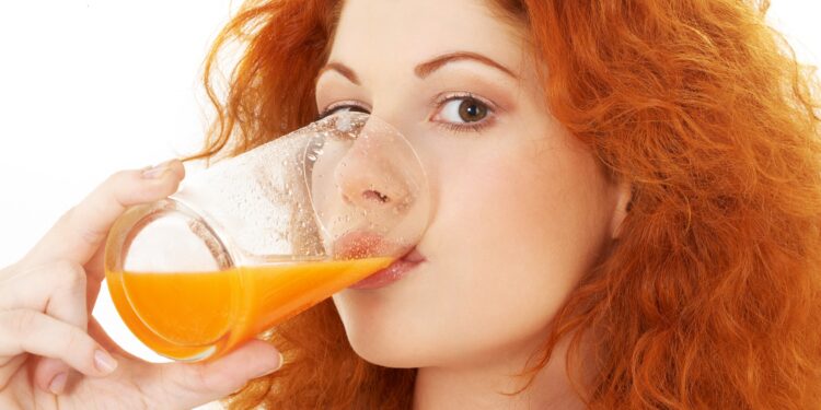 Rothaarige Frau trinkt ein Glas Orangensaft