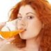 Rothaarige Frau trinkt ein Glas Orangensaft