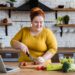 Übergewichtige Frau schneidet in der Küche Gemüse