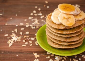 Einige Pancakes sind auf einem grünen Teller übereinander gestapelt.