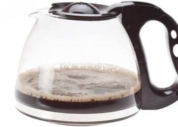 Kaffeekanne mit etwas schwarzem Kaffee vor weißem Hintergrund