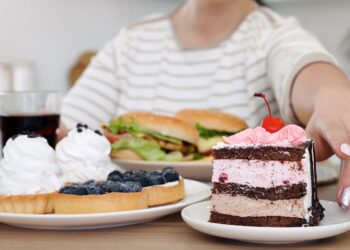 Eine Frau greift nach einem Teller, auf dem ein Stück Torte angerichtet ist.