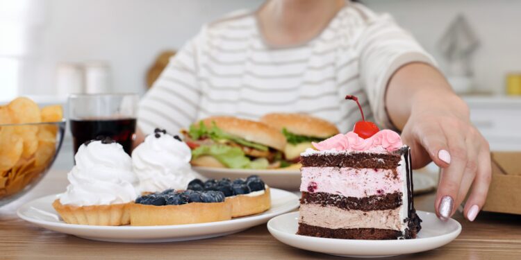 Eine Frau greift nach einem Teller, auf dem ein Stück Torte angerichtet ist.