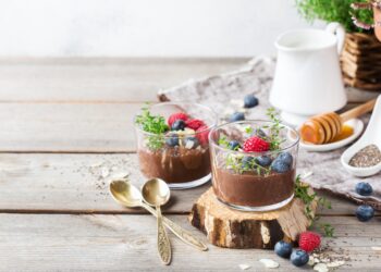 Zwei Portionen Chia-Schokoladen-Pudding sind auf einer hölzernen Oberfläche angerichtet.