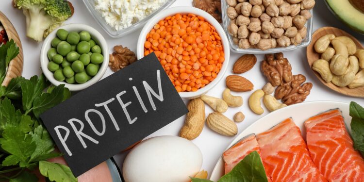 Verschiedene eiweißreiche Lebensmittel und ein Schild mit dem Wort Protein liegen auf einem Tisch