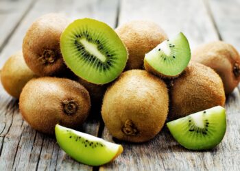 Frische ganze und aufgeschnittene Kiwis auf einem Holztisch