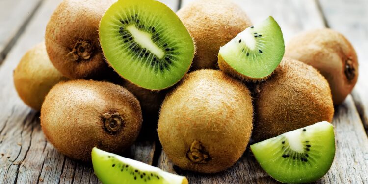 Frische ganze und aufgeschnittene Kiwis auf einem Holztisch