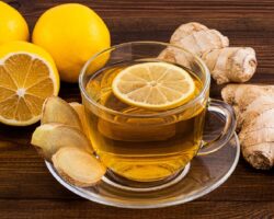 Eine Tasse mit frischem Ingwertee steht auf einer hölzernen Oberfläche.