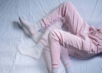 Eine Frau mit unruhigen Beinen liegt in einem Bett.