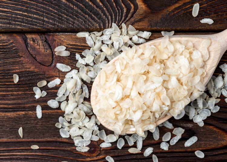 Reisflocken auf einem großen Holzlöffel.