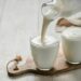 Pouring homemade kefir, buttermilk or yogurt with probiotics. Yogurt flowing from glass bottle on white wooden background. Probiotic cold fermented dairy drink. Trendy food and drink. Copy space left (Bild:  fascinadora/stock.adobe.com)