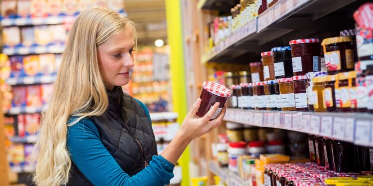 Junge Frau kauft Marmelade in einem Supermarkt.