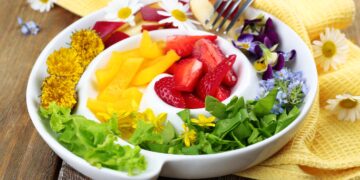 Auf einem Teller sind Obst und Gemüse in vielen unterschiedlichen Farben angeordnet.