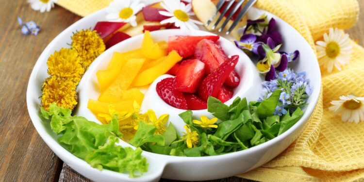 Auf einem Teller sind Obst und Gemüse in vielen unterschiedlichen Farben angeordnet.