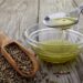 Pouring hemp oil into glass bowl and hemp seeds on wood