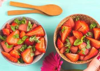 Ein Salat aus Wassermelone und Erdbeeren ist in zwei Schüsseln angerichtet.