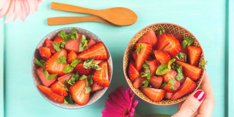 Ein Salat aus Wassermelone und Erdbeeren ist in zwei Schüsseln angerichtet.