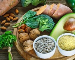 Auf einem Holzteller sind verschiedene Lebensmittel angerichtet, die reich an Vitamin E sind.