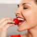 Eine Frau isst eine Erdbeere.