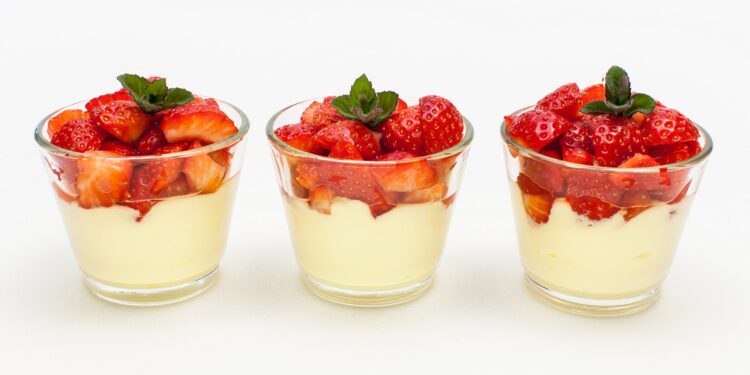 Panna cotta mit Erdbeeren in drei Gläsern vor weißem Hintergrund.