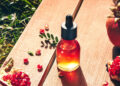 Granatapfelöl in einer medizinischen Flasche mit Granatapfel auf einem Holztisch