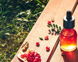 Granatapfelöl in einer medizinischen Flasche mit Granatapfel auf einem Holztisch