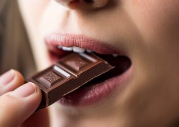 Eine Frau isst ein Stück Schokolade.