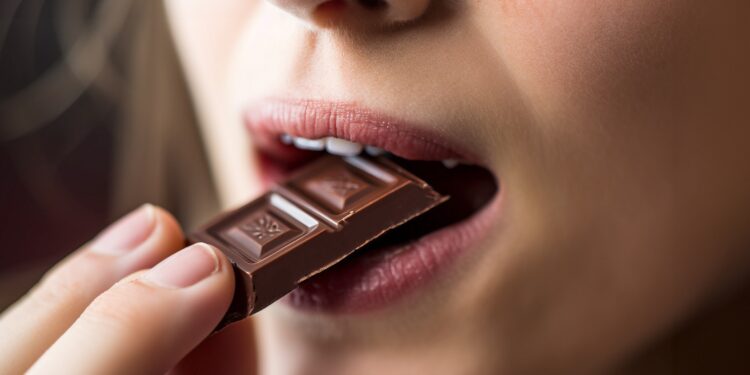 Eine Frau isst ein Stück Schokolade.