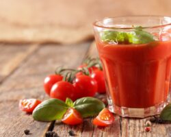 Ein Glas Tomatensaft mit Basilikum garniert.