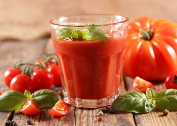 Ein Glas Tomatensaft mit Basilikum garniert.