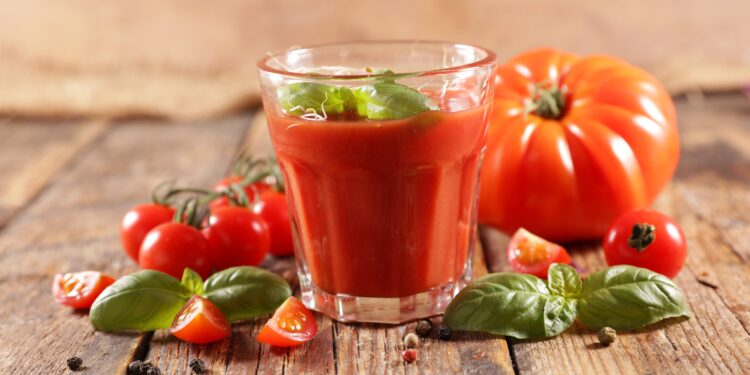 Ein Glas Tomatensaft mit Basilikum garniert.