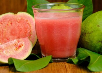 Guaven-Frucht und ein Glas mit Guavensaft in Großaufnahme.