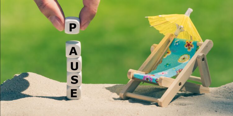 Liegestuhl am Strand mit Schirmchen und das Wort Pause aus Buchstabenwürfeln