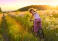 Frau fährt mit dem Rad durch sommerliches Feld