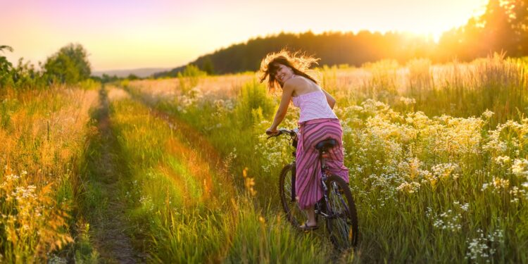 Frau fährt mit dem Rad durch sommerliches Feld