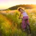Frau fährt mit dem Rad durch sommerliches Feld